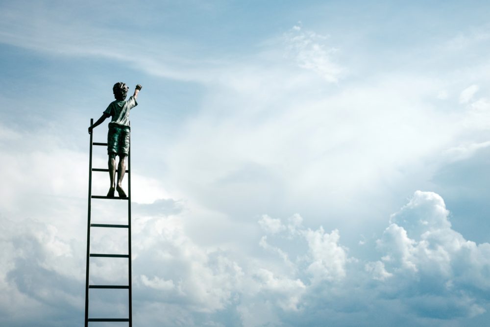 boy climbing a ladder to the clouds